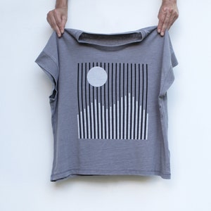 A women's gray boxy shirt with minimalist snowy mountain screenprint in black and white ink