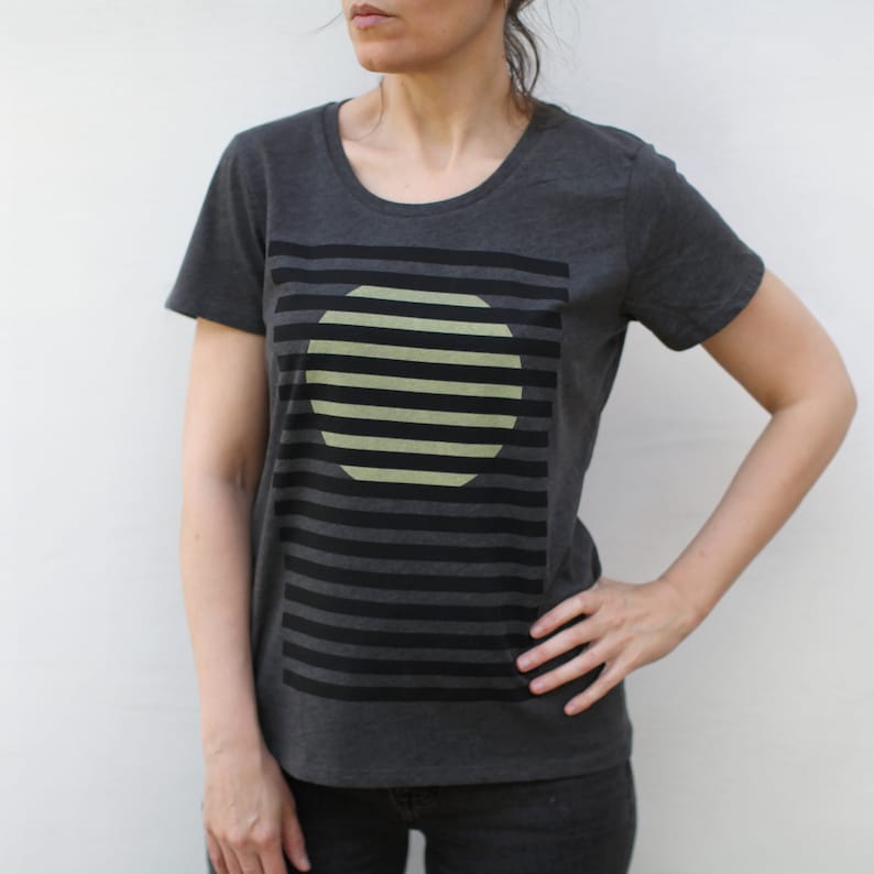 May include: A dark gray t-shirt with a graphic design of a yellow circle with black stripes on a black background.
