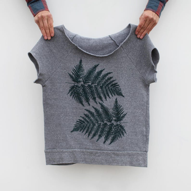 Puede incluir: Sudadera gris de manga corta con un dise&ntilde;o de hojas de helecho verde oscuro. La parte superior con cuello redondo tiene un ajuste relajado y est&aacute; hecha de un material suave. El dise&ntilde;o de helecho est&aacute; centrado en la parte delantera.