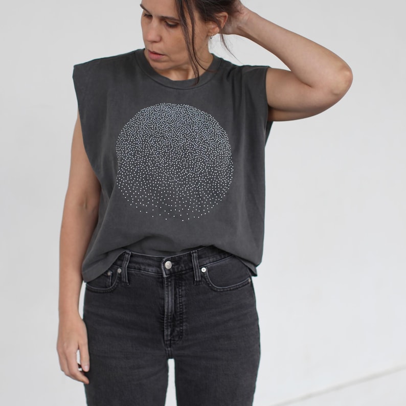Op de afbeelding: Een mouwloos t-shirt in antracietgrijs met een witte cirkelvormige afbeelding met een patroon van kleine witte stippen. Het shirt heeft een ontspannen pasvorm en een ronde hals.