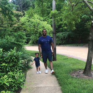 May include: A father and daughter walking down a sidewalk. They are both wearing matching Big and Little Dipper t-shirts in indigo blue.