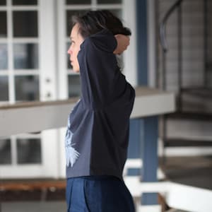 May include: A dark navy long-sleeve shirt with a light blue graphic design on the front. The shirt is paired with dark blue pants. The image is taken in natural light, with a blurred background.