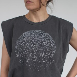 Op de afbeelding: Een mouwloos shirt in antracietgrijs met een wit cirkelvormig ontwerp gemaakt van kleine stippen. Het shirt heeft een losse pasvorm en een ronde hals.