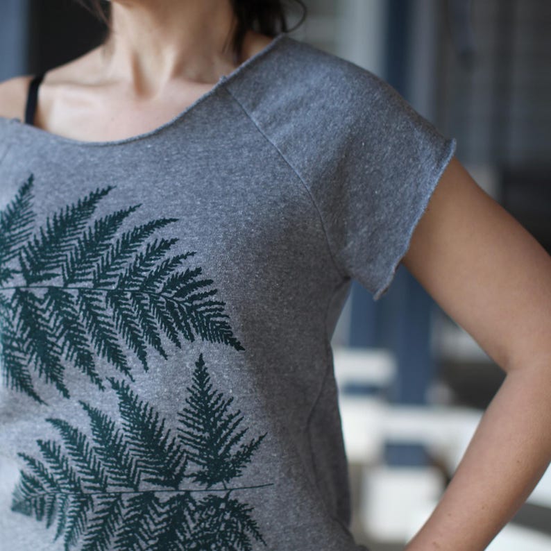 Puede incluir: Camiseta gris con un dise&ntilde;o de hojas de helecho verde oscuro. La camiseta tiene cuello redondo y mangas cortas con borde sin rematar. El dise&ntilde;o de helecho est&aacute; impreso en la parte delantera.