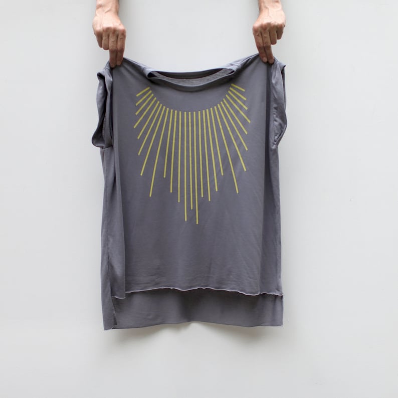 K&ouml;nnte beinhalten: Ein graues &auml;rmelloses Shirt mit einem gelben Sonnenstrahlen-Design auf der Vorderseite. Das Shirt hat einen l&auml;ngeren R&uuml;cken als die Vorderseite.