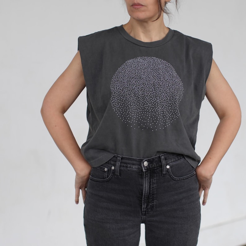 Op de afbeelding: Een mouwloos t-shirt in antracietgrijs met een wit cirkelvormig ontwerp gemaakt van kleine stippen. Het shirt heeft een ontspannen pasvorm en een licht ingekorte lengte.
