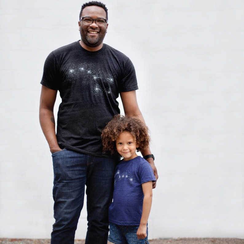 May include: A father and a child wearing black and indigo blue t-shirts with Big and Little Dipper constellation designs.