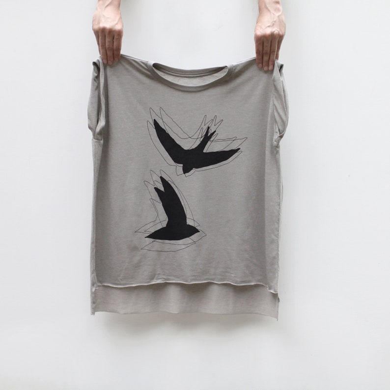 Bird Lover Shirt for Women. Two Chimney Swifts printed in black water based ink onto flowy loose fit muscle tees in beige. Features a crew neck, rolled cuffs, and a hi-low hem.