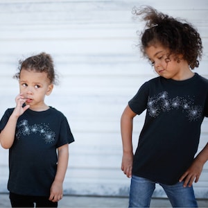 May include: Two sisters wearing matching Big and Little Dipper constellation t-shirts.