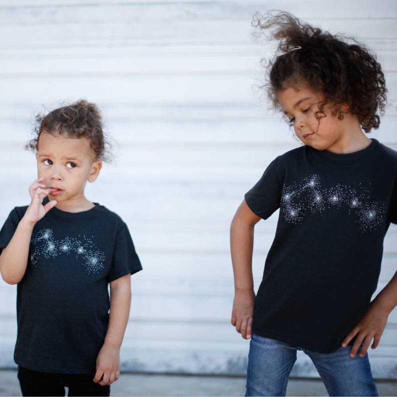 May include: Two sisters wearing matching Big and Little Dipper constellation t-shirts.