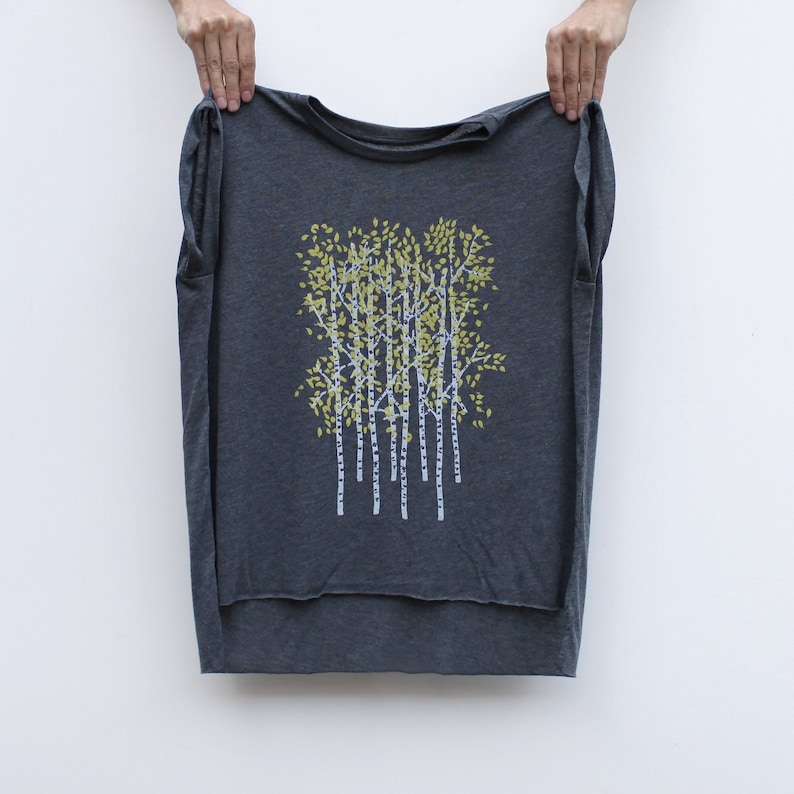 May include: A gray sleeveless shirt with a graphic print of a cluster of trees with yellow leaves and white trunks