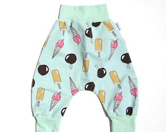 May include: Baby harem pants with an all-over ice cream print. The pants feature a light blue background with illustrations of ice cream cones, popsicles, and chocolate-covered ice cream bars in various colors. The waistband and cuffs are a solid light green.