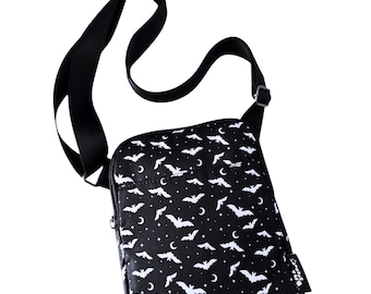 May include: Black crossbody bag with a white bat and crescent moon pattern. The bag has a zipper closure and an adjustable strap.