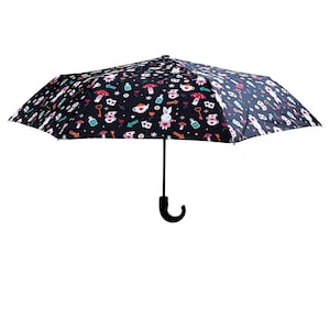 Puede incluir: Un paraguas negro con un conejo blanco, tazas de té y otras ilustraciones caprichosas. El paraguas tiene un mango negro con un gancho.