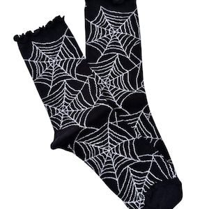 May include: A pair of black socks with a white spiderweb pattern. The socks have a ruffled top.