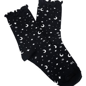 May include: A pair of black socks with a white crescent moon and star pattern. The socks have a frilly top.