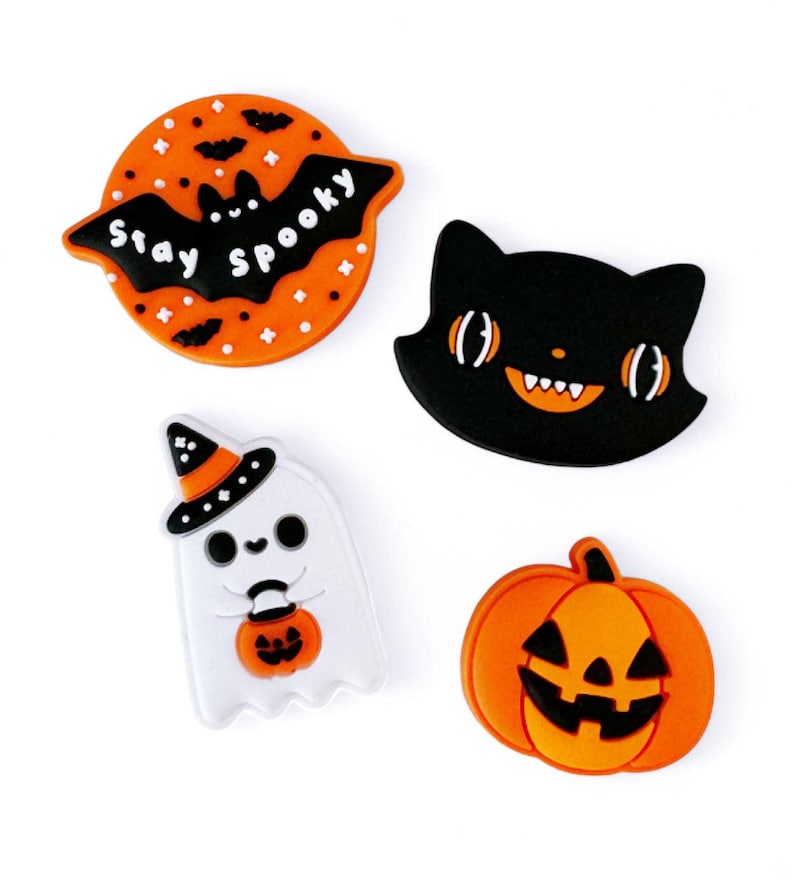 Peut inclure: Quatre breloques en silicone sur le th&egrave;me d'Halloween&nbsp;: un chat noir avec des dents orange, un fant&ocirc;me blanc avec un chapeau de sorci&egrave;re et une citrouille, une citrouille orange avec un visage de citrouille sculpt&eacute;e et une chauve-souris avec des ailes orange et le texte&nbsp;&laquo;&nbsp;Stay Spooky&nbsp;&raquo;.