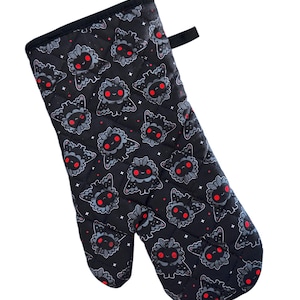 May include: Black oven mitt with a quilted design and a repeating pattern of cartoon black and red moth-like creatures with white stars on a black background.