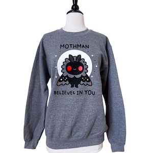 May include: Grey sweatshirt with a black mothman illustration and the text "Mothman believes in you".