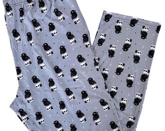 May include: Light gray pajama pants with an all-over pattern of black birds perched on white skulls. The pants have an elastic waistband and a relaxed fit, suitable for sleepwear or lounging.