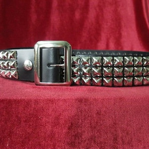 May include: A black leather belt with three rows of silver pyramid-shaped studs.