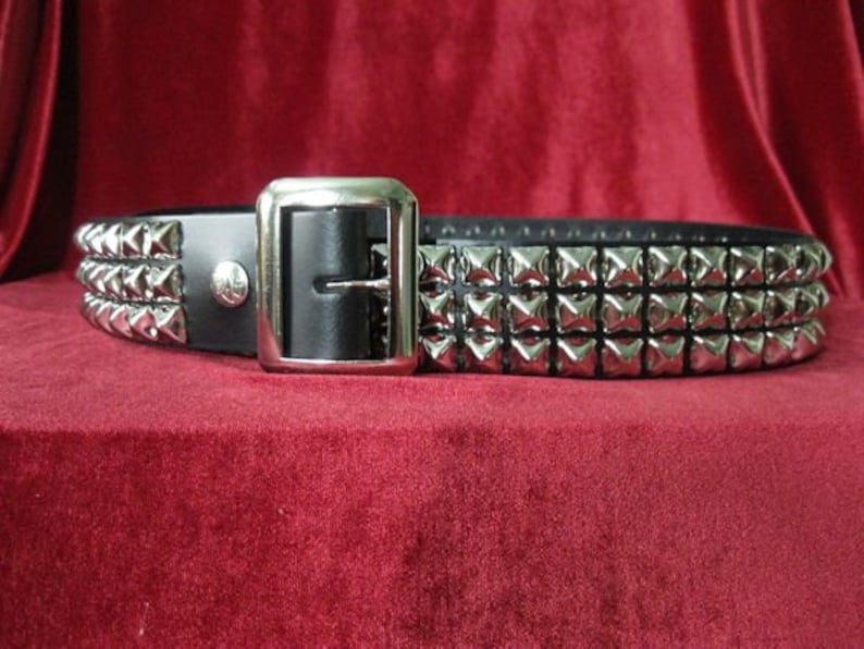 May include: A black leather belt with three rows of silver pyramid-shaped studs.