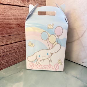Könnte beinhalten: Eine hellblaue Gable-Box mit einer Zeichentrickfigur, die Luftballons hält. Die Box hat ein pastellfarbenes Regenbogen- und Wolken-Design. Der Text "Gennesis 8" ist auf der Vorderseite der Box aufgedruckt.