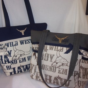 Puede incluir: Dos bolsos de mano con tem&aacute;tica western. Los bolsos est&aacute;n hechos de tela beige con un estampado marr&oacute;n y negro de un cr&aacute;neo de toro, estrellas y las palabras "Wild West", "Round 'Em Up" y "Haw." Los bolsos tienen detalles en tela azul oscuro y verde oscuro.