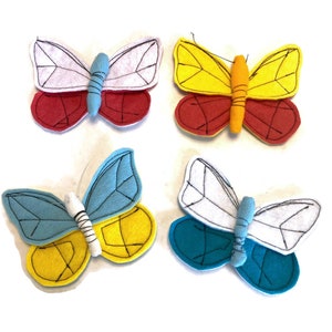 May include: Four felt butterflies in different color combinations. The butterflies are red, yellow, blue, and white. They are all sewn with black thread.