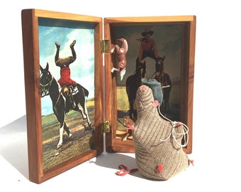May include: A wooden box with two open compartments. The left compartment contains a vintage photograph of a man riding a horse. The right compartment contains a small stuffed toy bird.