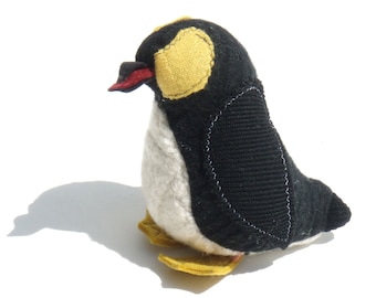 May include: A black and white penguin plush toy with yellow accents. The penguin has a red beak and a yellow patch on its head.