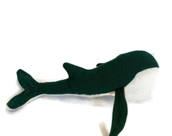May include: A plush whale toy made of dark green fabric with a white belly. The whale has a long tail and fins.