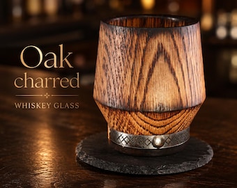 May include: A cylindrical whiskey glass crafted from charred oak wood, featuring a prominent wood grain pattern and a metallic band with a circular stud detail at the base. The text Oak charred WHISKEY GLASS is visible to the left of the object.