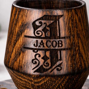 Close up engraved whiskey glass, personalized charred oak tumbler with deep wood carving and natural grain