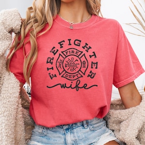 May include: A red t-shirt with a black firefighter emblem and the text "Firefighter wife".
