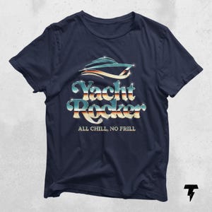 May include: A navy blue t-shirt with a silver and blue graphic of a yacht with the text "Yacht Rocker" and the phrase "All Chill, No Frill" underneath.