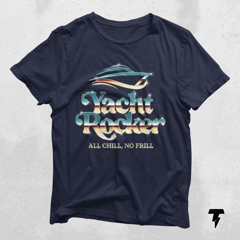 May include: A navy blue t-shirt with a silver and blue graphic of a yacht with the text "Yacht Rocker" and the phrase "All Chill, No Frill" underneath.