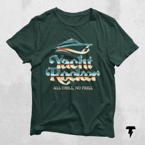 May include: A dark green t-shirt with a silver and blue graphic of a yacht with the text "Yacht Rocker" and the phrase "All Chill, No Frill" underneath.