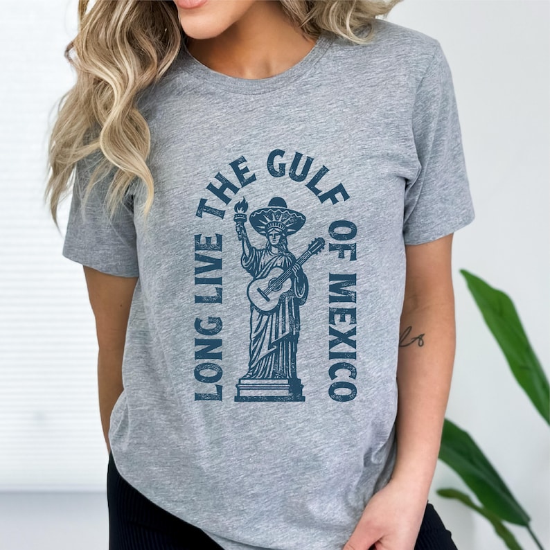 a woman wearing a grey t - shirt with a statue of liberty on it