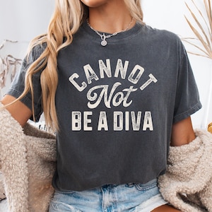 May include: A dark gray t-shirt with the text "CANNOT Not BE A DIVA" in white.