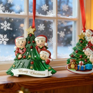 May include: Two Christmas tree ornaments with red ribbons. One features three figures with names, the other has seven figures. Both have a green tree design, gold stars, and the words "Merry Christmas".