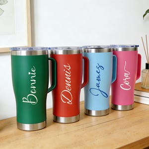Puede incluir: Cuatro vasos personalizados en verde, rojo, azul claro y rosa, cada uno con borde y asa plateados. Los nombres "Bonnie", "Dennis", "James" y "Cora" est&aacute;n escritos en cursiva en cada vaso.