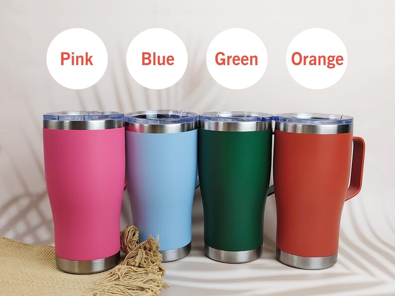 Puede incluir: Cuatro tazas de viaje de acero inoxidable en rosa, azul, verde y naranja. Cada taza tiene un asa y un borde y base plateados. Los colores est&aacute;n etiquetados encima de cada taza.