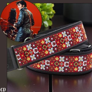 Op de afbeelding: Een zwarte gitaarband met een rood, wit en goud geometrisch patroon. De band is gemaakt van geweven stof en heeft zwarte leren uiteinden. Een afbeelding van een muzikant met een vergelijkbare band staat in de linkerbovenhoek.