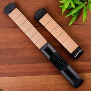 Könnte beinhalten: Zwei schwarze und holzfarbene Übungswerkzeuge für das Gitarrengriffbrett. Die Griffbretter sind helles Holz mit weißen Punktmarkierungen. Der schwarze Teil hat ein abgerundetes Ende und eine Reihe vertikaler Linien. Werkzeuge für das Gitarrenüben.