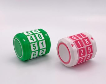 May include: Two combination locks, one green and one pink, each with white number blocks. The green lock displays numbers 0-6, while the pink lock shows numbers 0-9. Both locks have a circular design.