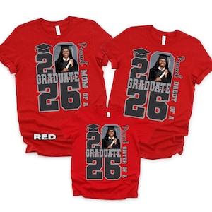 May include: Red t-shirts with a graduation theme. Each shirt features a photo of a graduate, the year "26", and the text "GRADUATE". The shirts also include the phrases "Proud Mom of a", "Proud Daddy of a", and "Proud Sister of a".