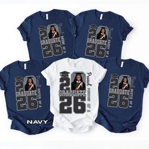May include: Navy and white t-shirts with a graduation theme. Each shirt features a graphic with the text "GRADUATE 26" and a photo of a graduate. The shirts also include text such as "Mom of a", "Daddy of a", "Sister of a", and "Bestie of a".