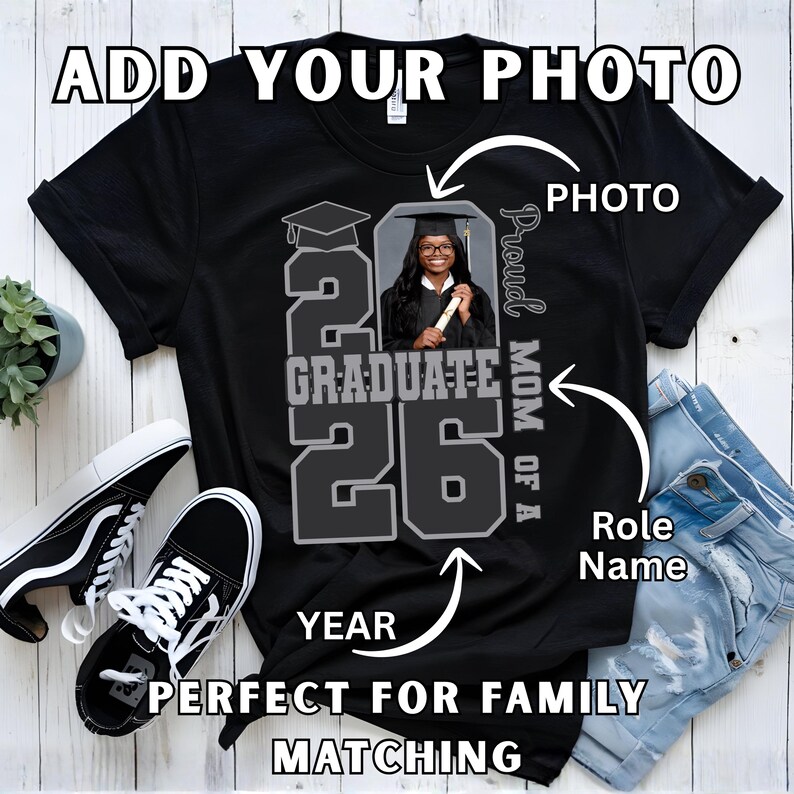 May include: Black t-shirt with a graduation design. The design includes the text "20 Graduate 26", a photo, and the words "Proud Mom of a". The shirt is next to a pair of black and white sneakers and a pair of blue jeans.