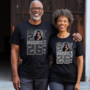May include: Two people wearing black t-shirts with a graduation theme. The shirts feature the text "2026 Graduate" with a photo and the phrases "Proud Dad of a" and "Proud Mom of a".